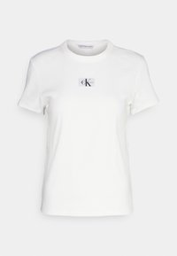 Bílý bavlněný tričko s kulatým výstřihem a krátkými rukávy. Obsahuje obdélníkovou nášivku s logem "CK" na přední straně.
