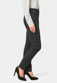 Zwarte op maat gemaakte broek met een slim fit, met een zachte textuur, ritssluiting details en gecombineerd met zwarte hoge hakken.