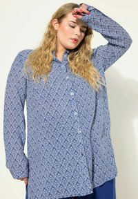 Camicia button-up blu con motivo, decorata con design geometrici bianchi, maniche lunghe e colletto classico, realizzata in tessuto leggero.
