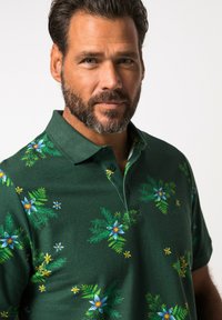 Zelená polo košile vyrobená z bavlny, s květinovými vzory v modré a žluté barvě, klasickým límečkem a zapínáním na tři knoflíky.