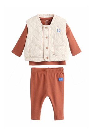 Beige quilted vest with buttons and pockets over rust-colored long-sleeve shirt and matching ribbed pants with elastic waistband.