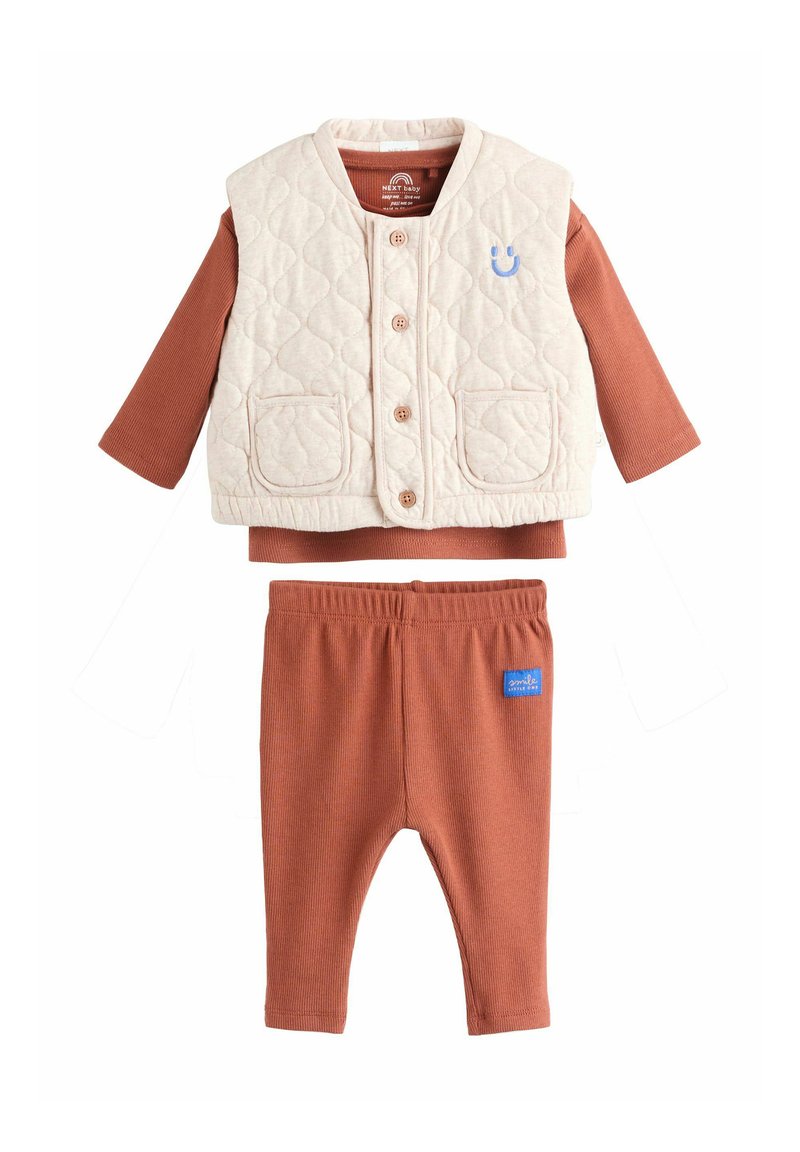 Beige quilted vest with buttons and pockets over rust-colored long-sleeve shirt and matching ribbed pants with elastic waistband.