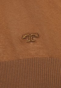 Brązowy sweter z dzianiny z prążkowanym dołem i haftowanym logo na środku. Materiał wydaje się miękki z lekko strukturą.