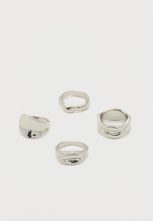 Fire skinnende sølvringe med uregelmæssige, organiske former arrangeret på en hvid overflade.