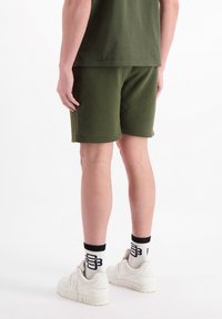 Olijfgroene shorts van zacht materiaal, met een relaxte pasvorm. Gecombineerd met witte sneakers en sportkousen met een logopatroon.