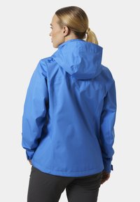 Niebieska wodoodporna kurtka z kapturem, prezentująca smukły design i gładką teksturę. Posiada logo na plecach oraz regulowane mankiety.