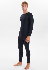 Black thermal long-sleeve top and fitted leggings. Soft fabric with a smooth texture, featuring a crew neck and cuffed sleeves.