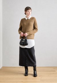 Barna bolyhos pulóver, fehér ing fölött, fekete farmer maxi szoknya, fekete bokacsizma és egy kicsi fekete kézitáska.