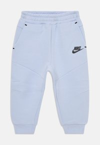 Šviesiai mėlyni Nike sportiniai kelnių su elastinga juosta, šoniniais kišenėmis ir logotipu dešinėje šlaunyje. Susigrūdinti rankogaliai ties kulkšnimis.