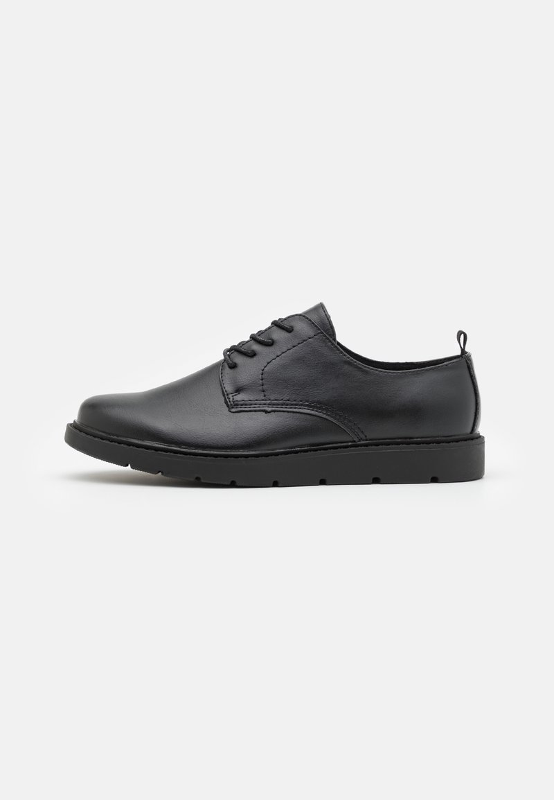 Chaussure basse en cuir noir à lacets avec bout arrondi et semelle épaisse en caoutchouc, vue de l'intérieur sur fond blanc.