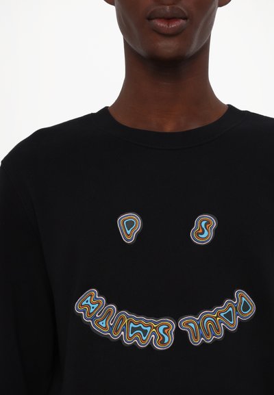 Sudadera negra con texto ondulado y colorido, y gráfico de carita sonriente. Material suave de mezcla de algodón con cuello y puños acanalados.