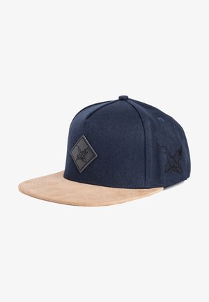 Gorra azul marino hecha de tela con visera plana beige. Presenta un parche de diamante negro y un diseño bordado en el costado.
