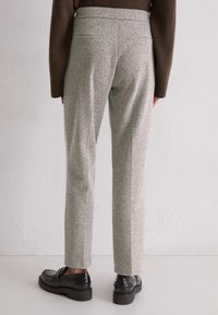 Szare, teksturowane spodnie charakteryzują się slim fit, mają gładką talię i tylne kieszenie, dopełnione czarnymi mokasynami.