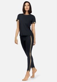 Czarny zestaw odzieży sportowej, składający się z koszulki z krótkim rękawem z złotymi akcentami oraz dopasowanych legginsów z złotymi paskami po bokach. Gładki, lekki materiał.