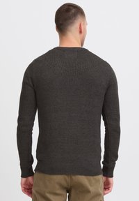 Suéter de punto gris oscuro con cuello redondo, puños y dobladillo acanalados, que presenta un diseño simple y texturizado. La vista trasera muestra una silueta ajustada.