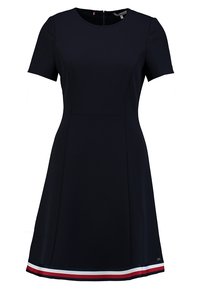 Vestido de navy de manga corta con cuerpo ajustado y falda acampanada, que presenta un dobladillo a rayas en rojo, blanco y azul para contraste. Cierre de cremallera en la parte posterior.
