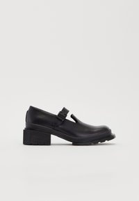 Black leather shoe with an open toe, featuring a side buckle and a chunky heel with a textured surface. Smooth finish, minimalist design.