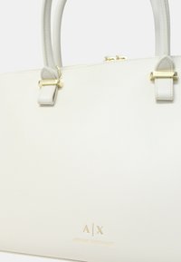 Borsa a mano in pelle bianca con hardware dorato, dotata di manici doppi e logo impresso "A/X ARMANI EXCHANGE" sul davanti.