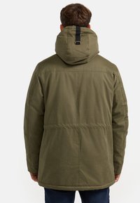 Chaqueta con capucha de color verde oliva, con un diseño acolchado, que cuenta con un detalle de correa negra en la parte posterior y un dobladillo recto.