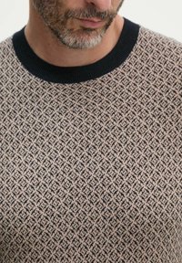 Maglione beige con un motivo a diamante in blu navy. Presenta un colletto a coste blu navy. Il materiale sembra avere una trama e sia traspirante.