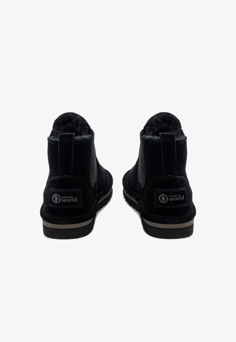 Zwarte suède enkelboots met een zachte voering, elastische zijpanelen en een rubberen zool met een contrasterende beige rand en branding.
