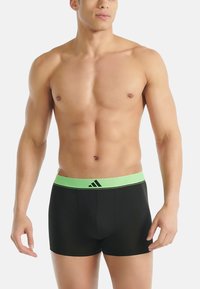 Černé boxerky s elastickým pasem v zelené barvě, lehce texturované a s výrazným logem Adidas.