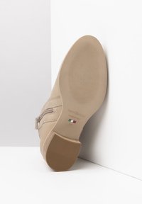 Bottine en cuir beige avec une fermeture éclair sur le côté, semelle texturée et petit talon. Marque "NeroGiardini," fabriquée en Italie, taille 37.