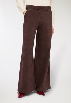 Pantaloni marroni a gamba larga con una texture liscia e vita elasticizzata, abbinati a scarpe rosse lucide. Design semplice, senza motivi visibili.