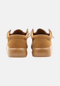 Des chaussures de sport en daim marron avec des talons arrondis et une semelle en caoutchouc lisse, sans lacets visibles et avec un minimum de détails de couture.