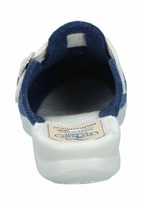 Navy and cream felt slip-on shoe with a back strap and a white rubber sole, featuring a textured interior and branded tag.