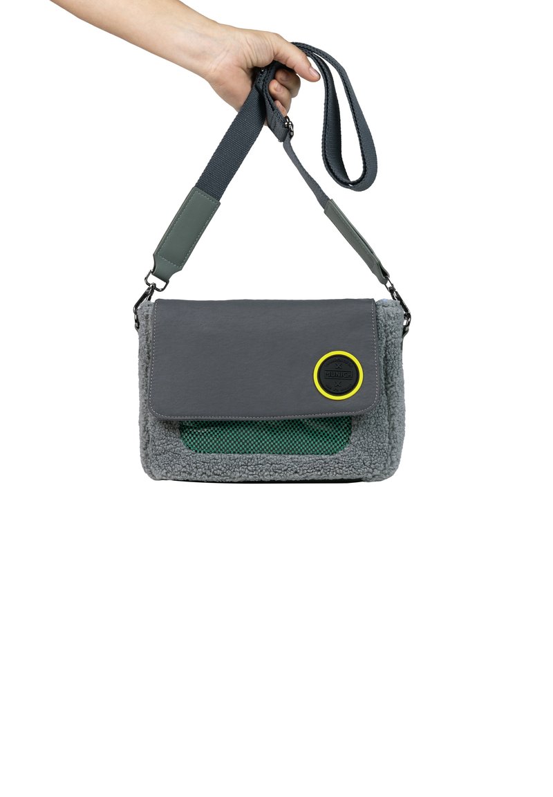 Bolso bandolera gris y verde con una solapa, tejido texturizado, bolsillo de malla y un distintivo circular. Incluye una correa de hombro ajustable.