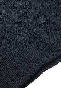 Tumma laivastonsininen teksturoitu viltti, jossa on kudottu kuvio, paksu neulottu muotoilu ja pehmeä, kosketeltava pinta. Reunat on viimeistelty siististi.