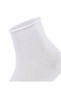 Vit bomullsocka till ankeln med ribbad textur, med en slät mudg och en åtsittande form. Lätt och ventilerande design för komfort.