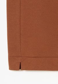 Hnědá tkanina s texturovaným úpletem, s rovnou hranou a malým výřezem na spodním okraji pro designový efekt.