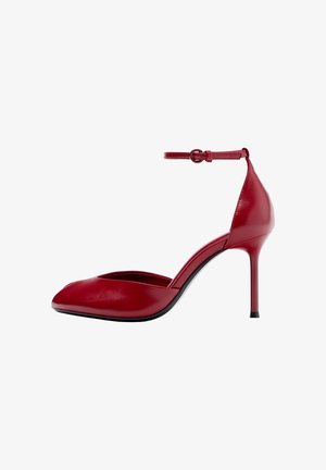 Rode leren hoge hakken met puntige neus en enkelbandje, slanke stilettohak, afgebeeld op witte achtergrond.