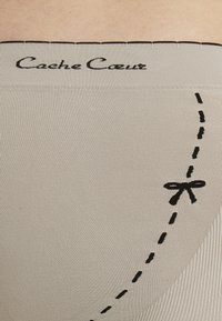 Beige Ripp-Leggings mit einem schwarzen bestickten Taillenbund. Verfügt über eine genähte Linie und eine Schleifendetail an der Seite. Glatte Textur.