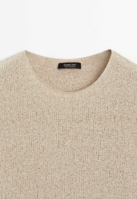 Pull beige en laine, col rond, avec une étiquette Massimo Dutti cousue à l'intérieur du col, fabriqué au Maroc.