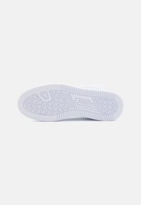 Talpa de adidași albi cu cauciuc texturat pentru aderență. Prezintă un model stilizat și un logo. Margini ușor ridicate pentru stabilitate.
