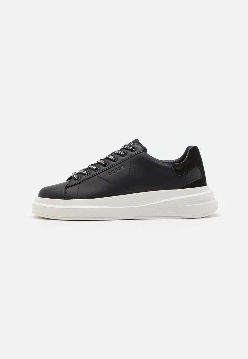 Zapatilla de cuero negra con suela de goma blanca, con cordones planos y ojales de marca. Textura suave con un acento lateral contrastante.