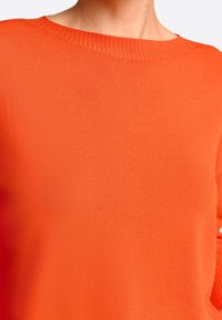 Oranje gebreide trui met een ronde halslijn en geribbelde afwerking. Gladde textuur zonder patronen of hardwaredetails.