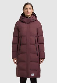 Tumepunane kapuutsiga sulejope, millel on kõrge kaelus, lukuga taskud ja isoleerimiseks tikkimismuster.