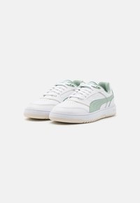 White sneakers with light green accents, smooth leather upper, lace-up design, perforated toe box, and a textured rubber sole.