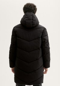 Manteau noir en doudoune avec capuche, présentant un motif en chevrons, des manches longues et une coupe mi-longue. Texture lisse avec une finition mate.
