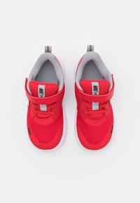 Scarpe sportive rosse in rete con un interno grigio imbottito. Presenta una chiusura in velcro, punta arrotondata e dettagli neri a contrasto.