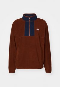 Pullover in pile marrone con pannello blu navy, colletto con mezza zip e dettagli del logo. Presenta una vestibilità rilassata e tasche laterali per la funzionalità.