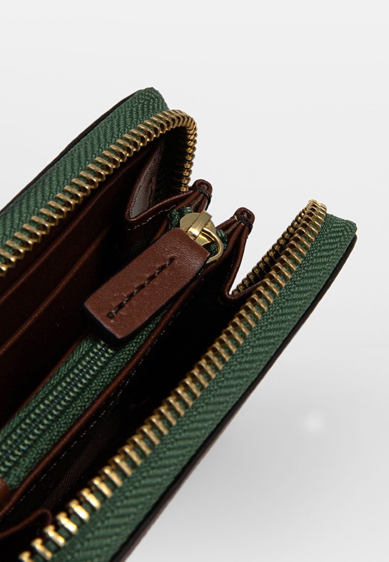 Billetera verde con una capa exterior texturizada, detalles en cuero marrón, cremallera dorada y múltiples compartimentos visibles desde un ángulo abierto.