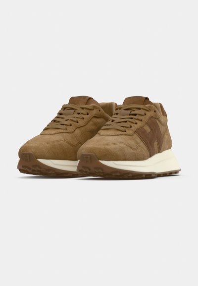 Brūnas zamšādas sporta kurpes ar fakturētām virsmām, baltu vidējo zolīti un brūnu gumijas ārpusi, ar nelielu logotipu sānos.