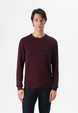 Maroon knit sweater with a round neckline and long sleeves, featuring a small logo accent on the chest and ribbed cuffs and hem.