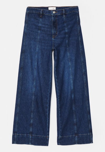 Pantalones vaqueros de pierna ancha en azul oscuro con costuras en contraste, cierre de botón y dobladillo liso. Fabricados con un material de algodón resistente.