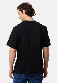 Zwart katoenen T-shirt met een relaxed fit. Korte mouwen, een ronde hals en een gladde textuur. Zichtbare stiksels langs de randen.